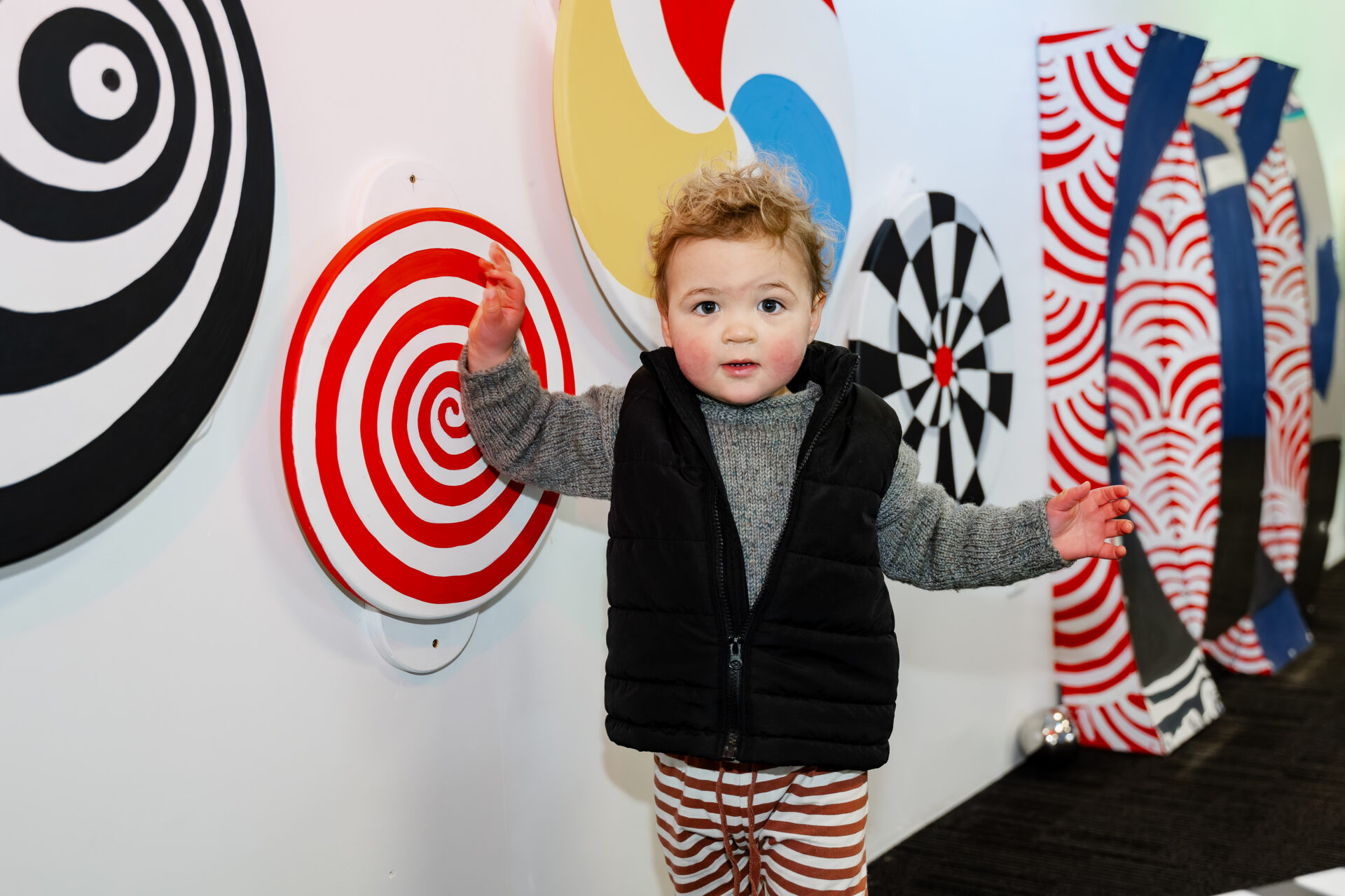 A child playing by a wall covered in spinning disks in PlayHQ.