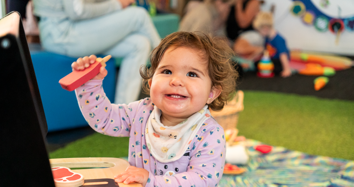 A child in PlayHQ playing with a toy barbecue.