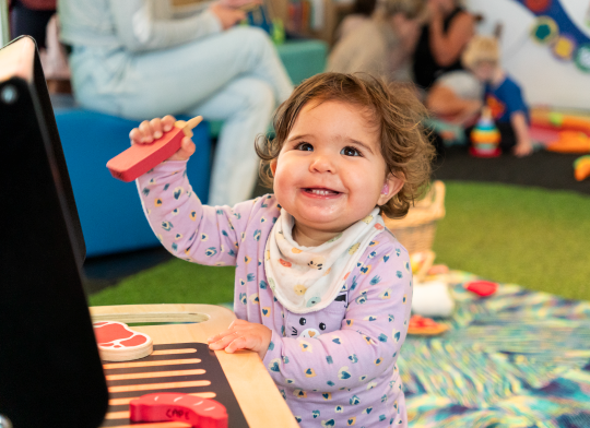 A child in PlayHQ playing with a toy barbecue.