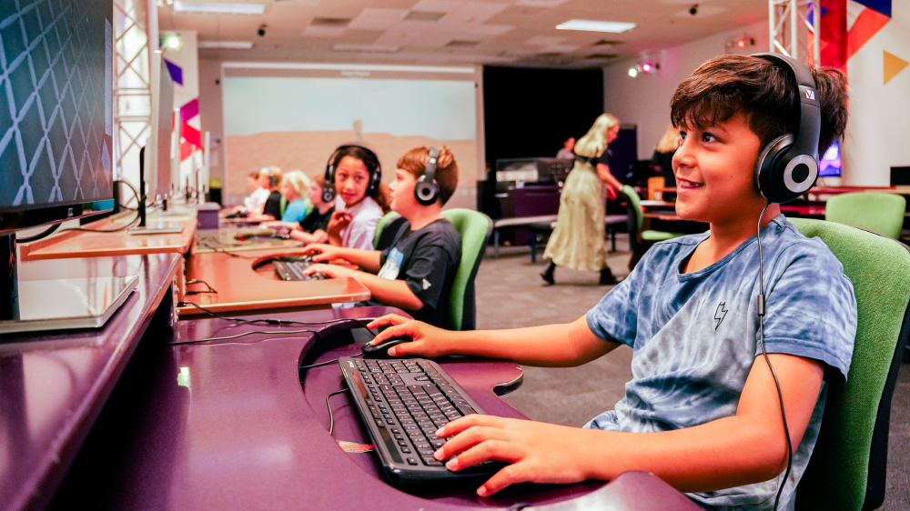 A child using a computer in the MediaLab, smiling.