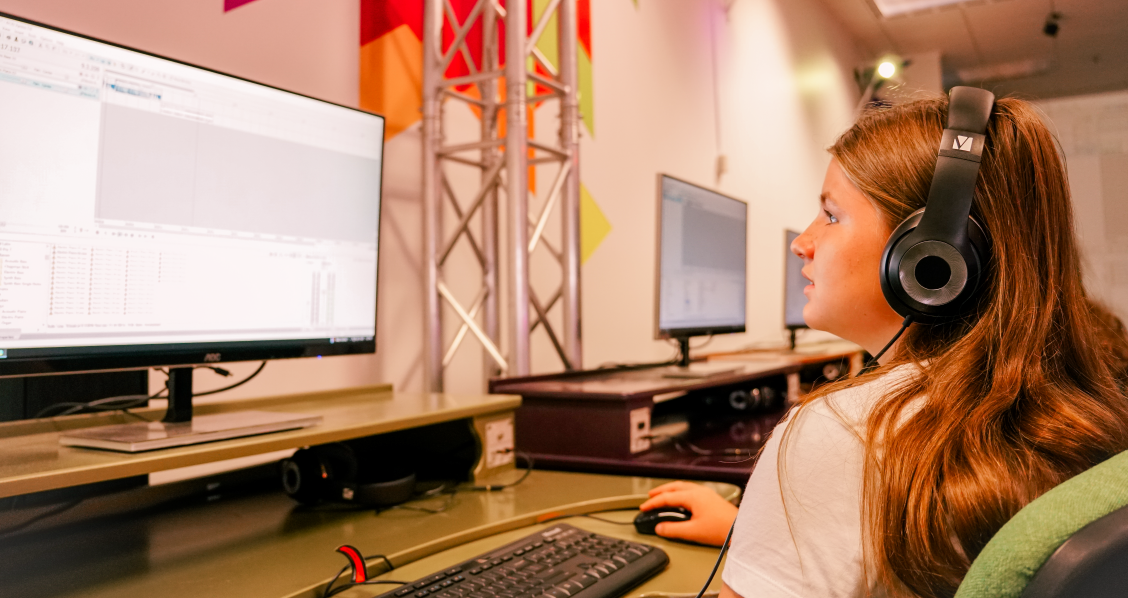 A girl wearing headphones, using a computer to make digital music