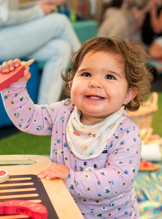 A child in PlayHQ playing with a toy barbecue.