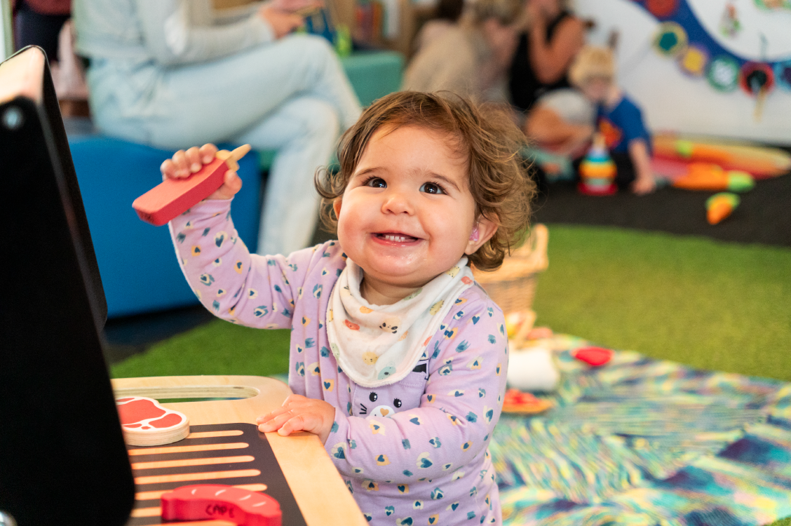 A child in PlayHQ playing with a toy barbecue.